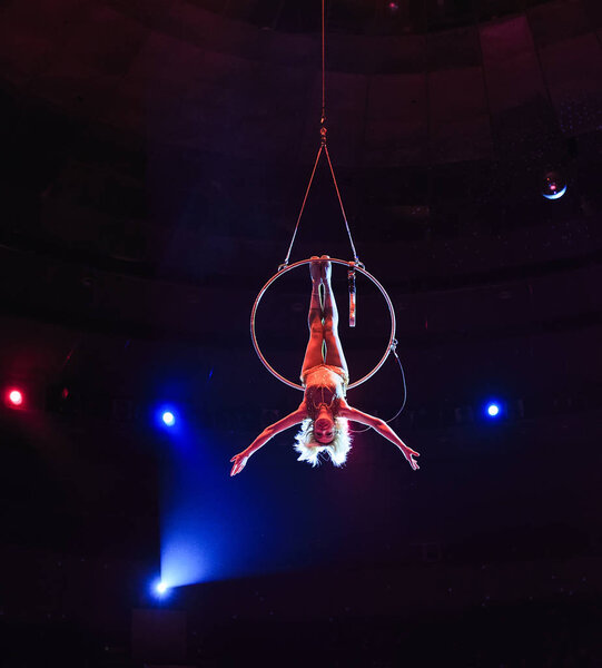 Aerial acrobat in the ring. A young girl performs the acrobatic elements in the air ring