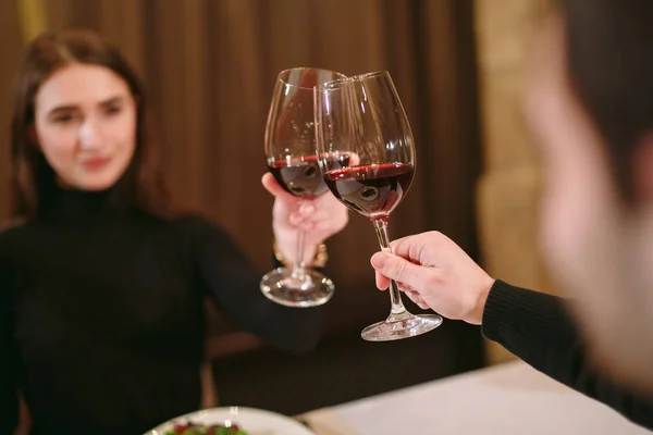 Belo jovem casal com copos de vinho tinto em restaurante de luxo — Fotografia de Stock