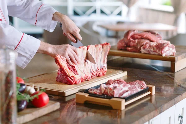 Um homem cozinha corta carne com uma faca em um restaurante . — Fotografia de Stock