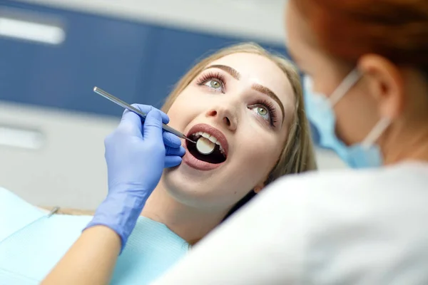 Kvinnlig tandläkare kontrollera patientens flicka tänder i en klinik — Stockfoto