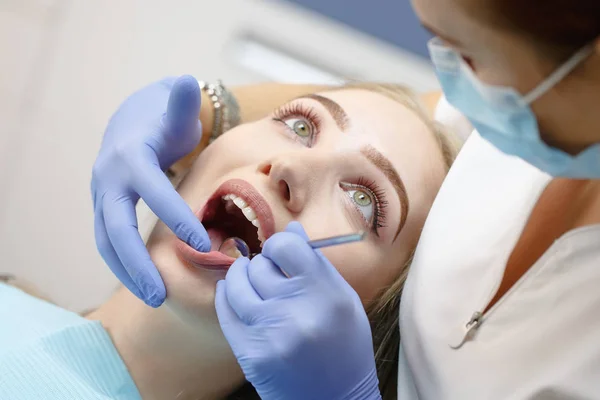 Dentista femenino revisando dientes de niña paciente en una clínica — Foto de Stock