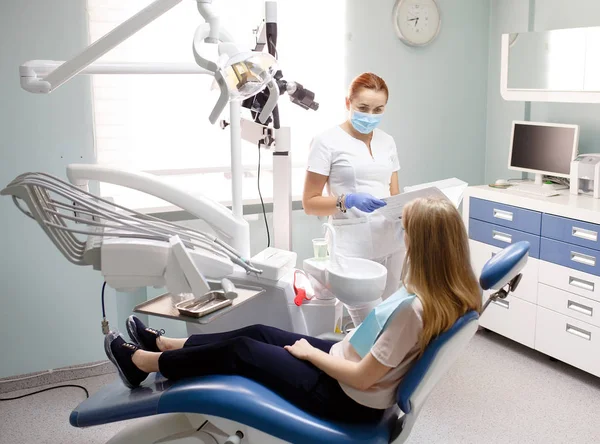 Dentista femenina con paciente niña hablando en el consultorio de la clínica dental . — Foto de Stock