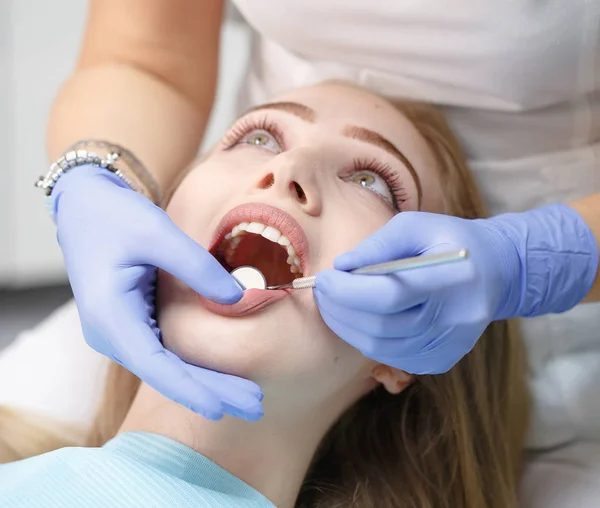 Dentista femenino revisando dientes de niña paciente en una clínica — Foto de Stock