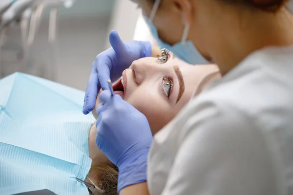 Dentista femenino revisando dientes de niña paciente en una clínica — Foto de Stock