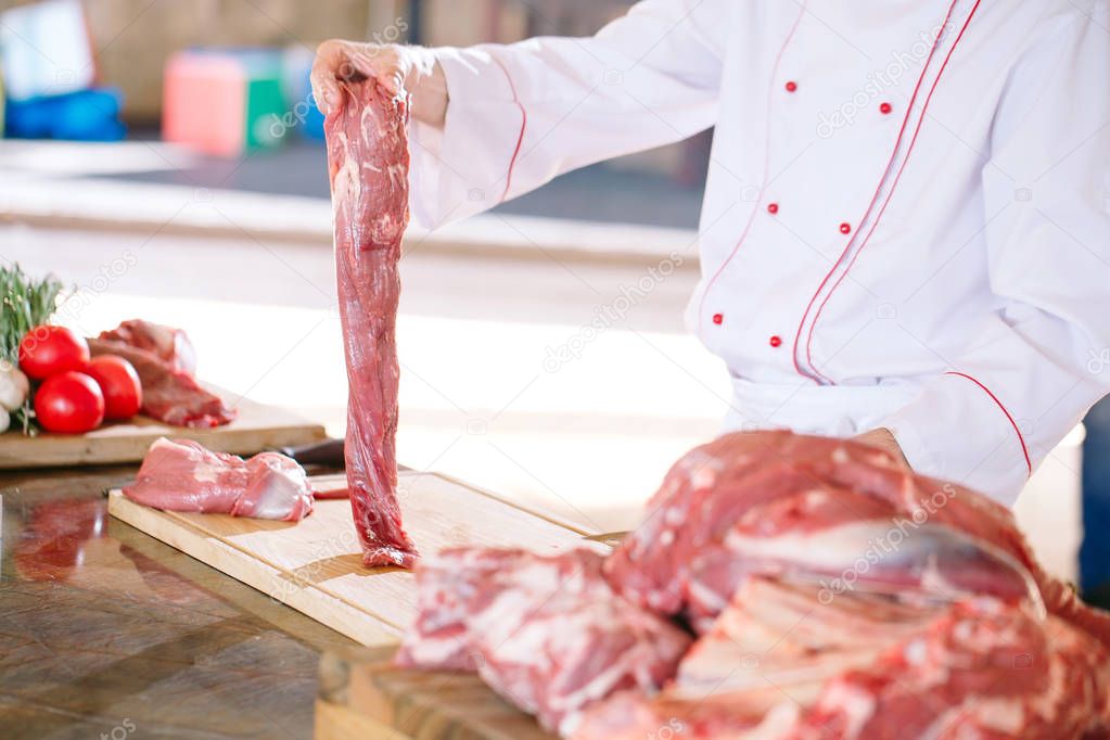 A man cook cuts meat with a knife in a restaurant