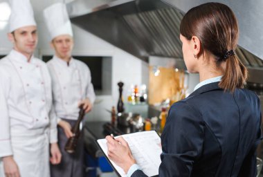 Restoran müdürü, mutfak personeline ticari mutfakta brifing veriyor..