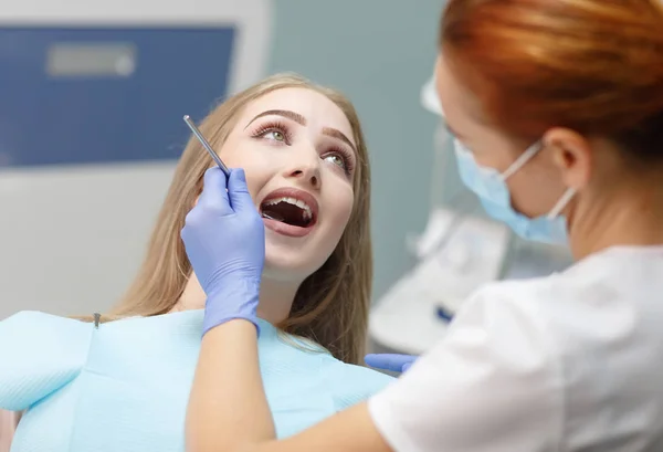 Female dentist checking patient girl teeth in a clinic — Stock Photo, Image