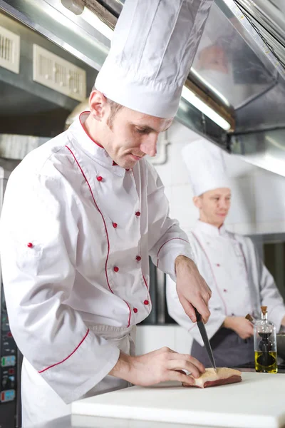 Chef cutting meat on chopping board, professional cook holding knife and cutting meat in restaurant. — Stock Photo, Image