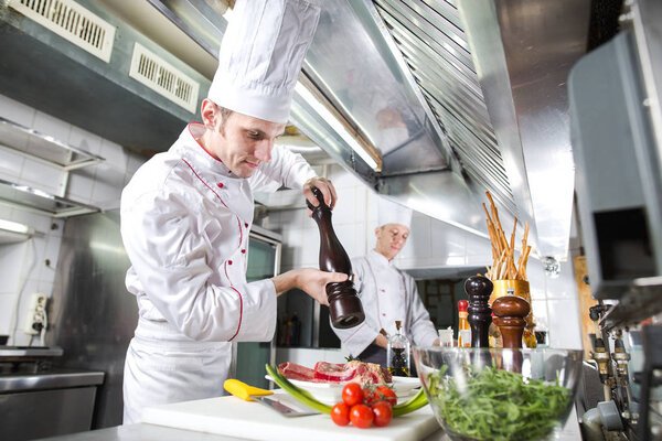The chef prepares a dish in the kitchen of restoran.