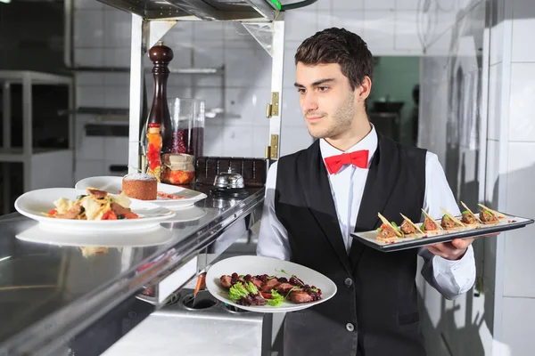Il cameriere con i piatti pronti nella cucina del ristorante — Foto Stock