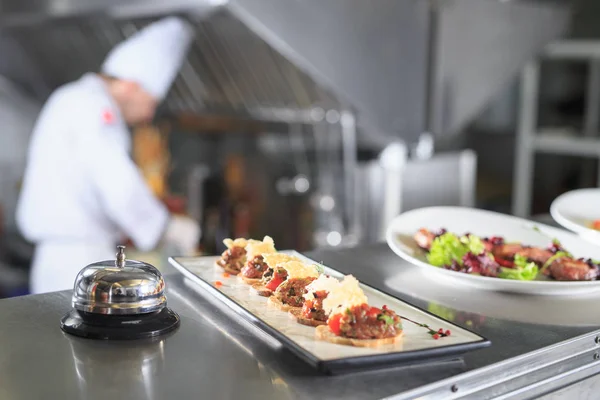 La mesa de distribución en la cocina del restaurante. el chef prepara una comida en el fondo de los platos terminados — Foto de Stock