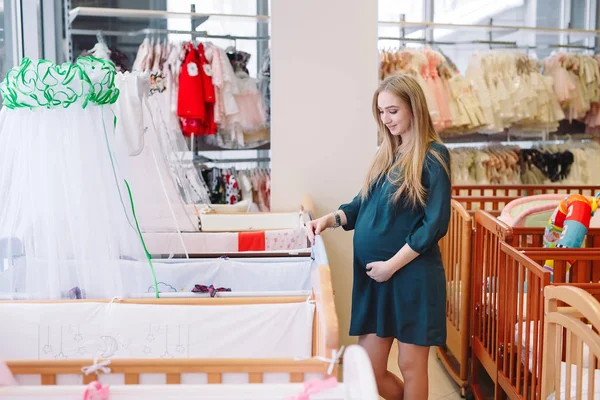 Беременная девушка выбирает детскую кроватку в магазине . — стоковое фото