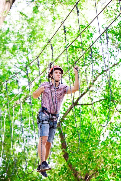 Aventura escalada alto fio parque - pessoas em curso em capacete de montanha e equipamentos de segurança — Fotografia de Stock