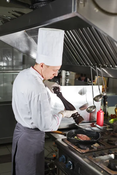 Chef in restaurant kitchen at stove with pan, cooking — Stock Photo, Image