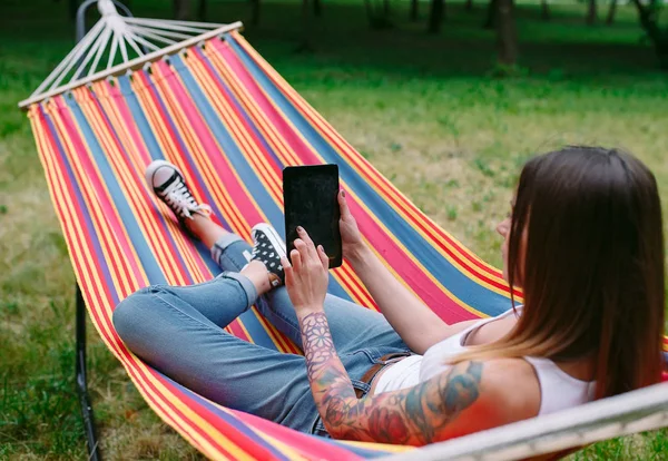 Jonge vrouw met tablet op de hangmat. — Stockfoto