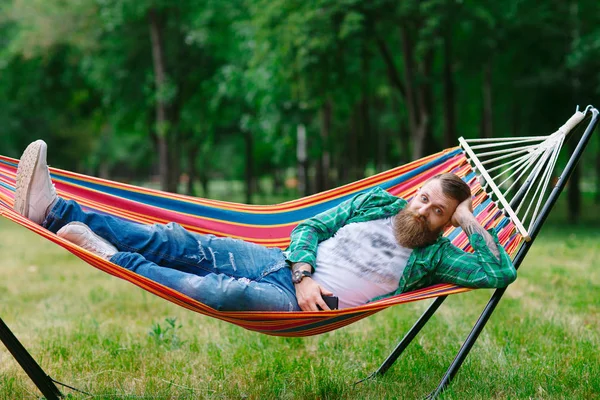 The man is lying on a hammock.