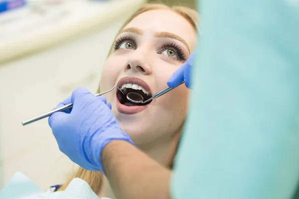 Photo en gros plan de la jeune femme assise dans la chaise des dentistes avec la bouche ouverte au bureau des dentistes tout en ayant un examen — Photo