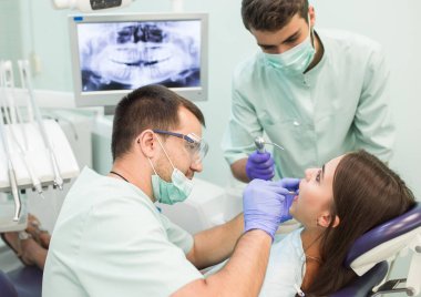 Doktor Dişçi ve asistanı bir diş kliniğinde çalışıyor.