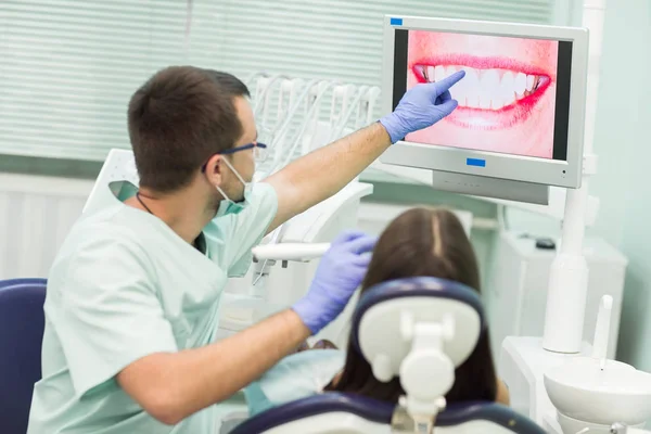 Mujer joven sentada en la silla de dentistas con la boca abierta en la oficina de dentistas mientras se somete a examen . — Foto de Stock