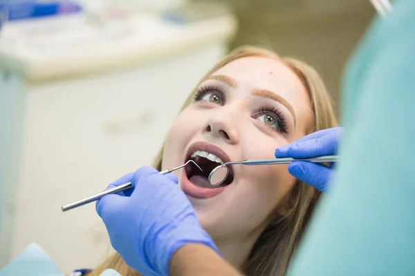 Närbild av ung kvinna sitter i tandläkare stolen med öppnade munnen på tandläkare kontor samtidigt ha undersökning — Stockfoto