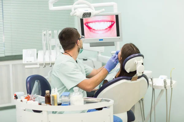 Mujer joven sentada en la silla de dentistas con la boca abierta en la oficina de dentistas mientras se somete a examen . — Foto de Stock
