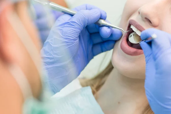 Imagen de cerca de una joven sentada en la silla del dentista con la boca abierta en el consultorio del dentista mientras se somete a examen — Foto de Stock