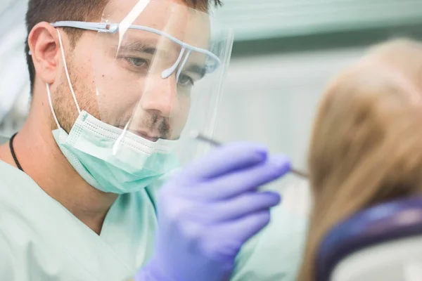 Close-up picture of young woman sitting in the dentists chair with opened mouth at dentists office while having examination — Stock Photo, Image