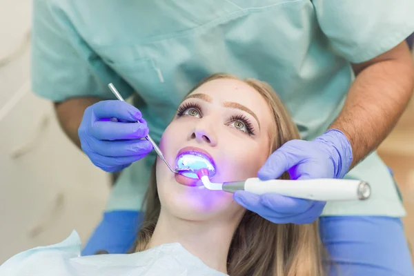Стоматолог проводить процедуру з лікуванням зубів ультрафіолетовим світлом в клініці — стокове фото