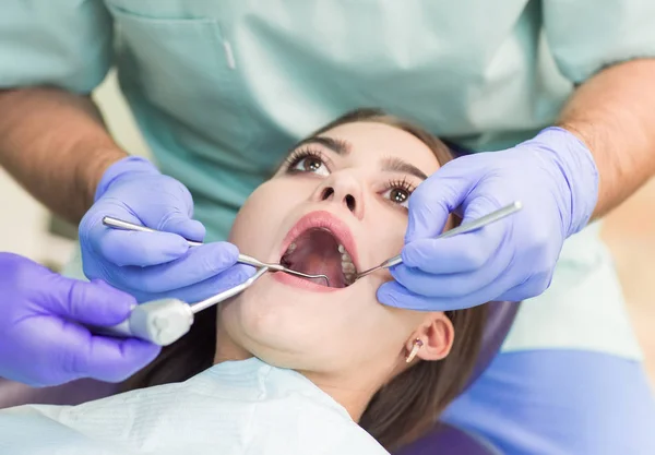 Imagen de cerca de una joven sentada en la silla del dentista con la boca abierta en el consultorio del dentista mientras se somete a examen — Foto de Stock