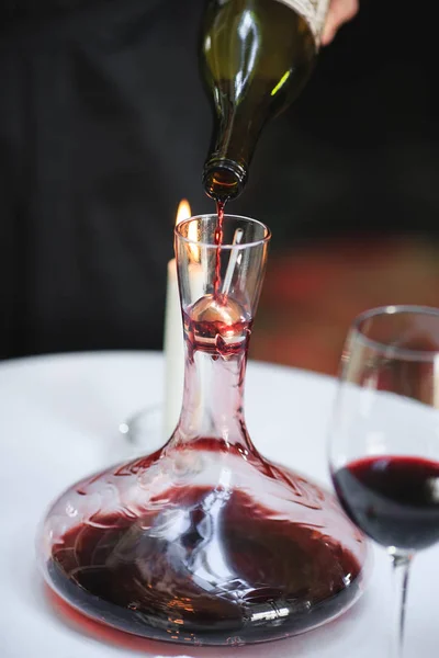 Un sommelier verse du vin rouge dans une carafe — Photo