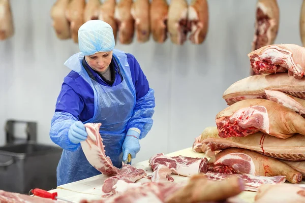 Snijden van vlees in slachthuis. Slager snijden varkensvlees bij de vleesproductie. — Stockfoto