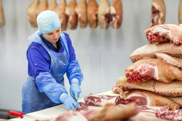 Cutting meat in slaughterhouse. Butcher cutting pork at the meat manufacturing. — Stock Photo, Image