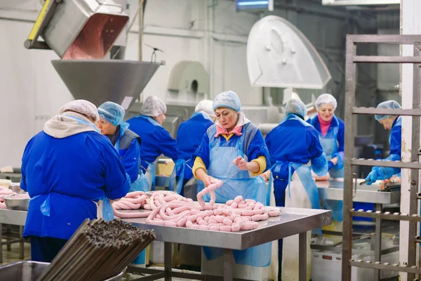 Macellai che lavorano salsicce nella fabbrica di carne . — Foto Stock