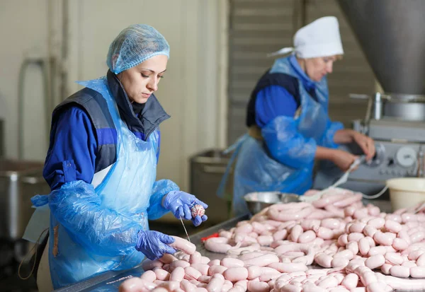 Macellai che lavorano salsicce in una fabbrica di carne . — Foto Stock