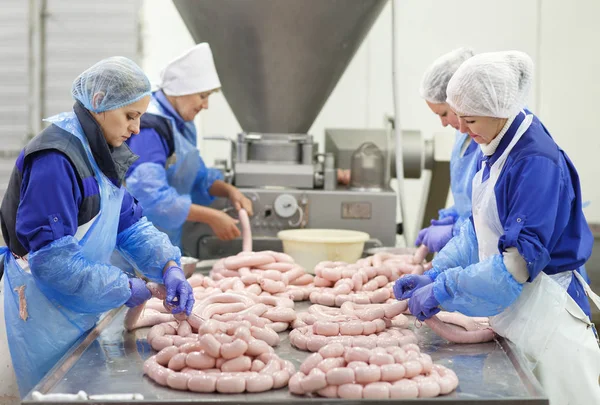 Macellai che lavorano salsicce in una fabbrica di carne — Foto Stock