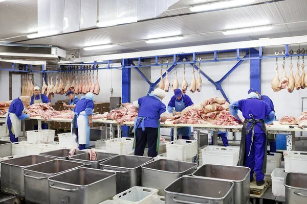 Cortar carne en el matadero. Carnicero cortando carne de cerdo en la fabricación de carne . — Foto de Stock