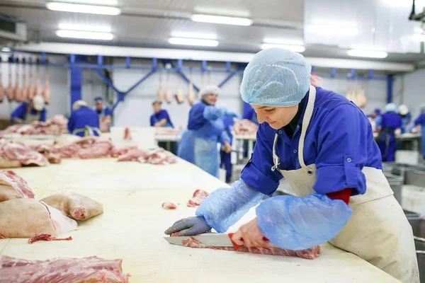 Cutting meat in slaughterhouse. Butcher cutting pork at the meat manufacturing. — Stock Photo, Image