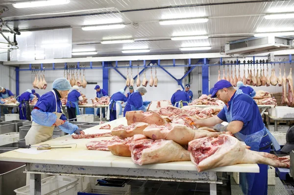 Cutting meat in slaughterhouse. Butcher cutting pork at the meat manufacturing. — Stock Photo, Image