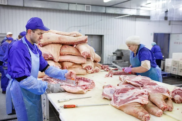 Cutting meat in slaughterhouse. Butcher cutting pork at the meat manufacturing. — Stock Photo, Image