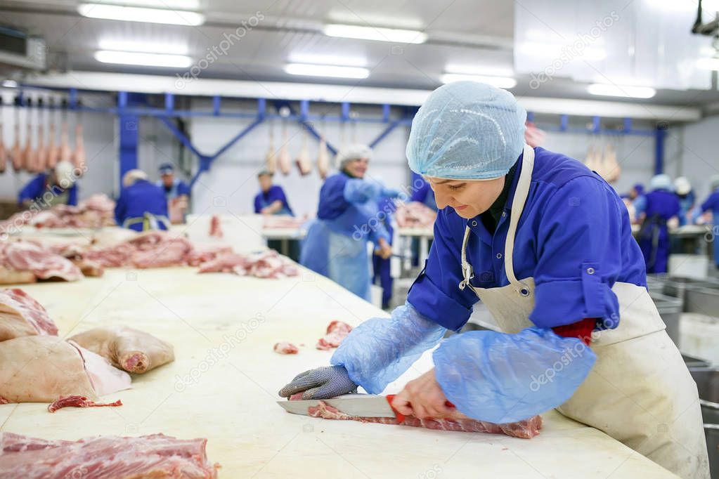 Cutting meat in slaughterhouse. Butcher cutting pork at the meat manufacturing.