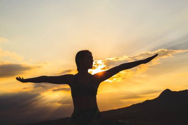 Genç kadının gün batımında veya gün doğumunda yoga ya da pilates yapan silueti, güzel bir dağ yerinde, lunge egzersizi yapıyor, Warrior ayakta