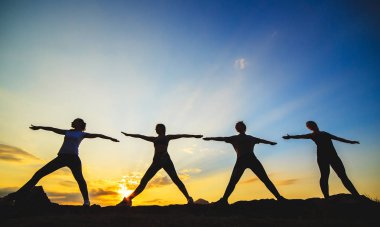 Güzel dağ yerinde gün batımında veya gün doğumunda yoga veya pilates yapan genç kadın silueti.