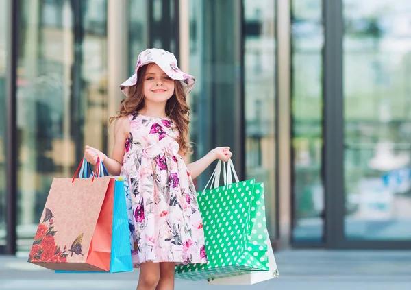 Aranyos kislány a vásárlás. Portréja egy gyerek a bevásárló szatyrok. Vásárlás. lány. — Stock Fotó