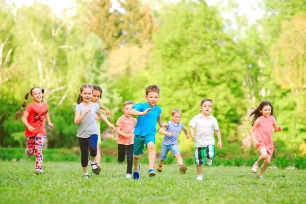 Багато різних дітей, хлопчиків і дівчаток біжать в парку в сонячний літній день в повсякденному одязі — стокове фото