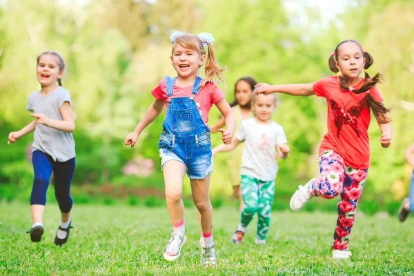 Viele verschiedene Kinder, Jungen und Mädchen, die an sonnigen Sommertagen in Freizeitkleidung durch den Park laufen — Stockfoto