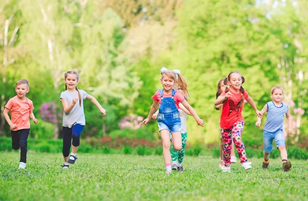 Багато різних дітей, хлопчиків і дівчаток біжать в парку в сонячний літній день в повсякденному одязі . — стокове фото
