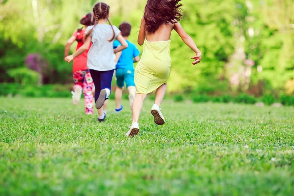 Viele verschiedene Kinder, Jungen und Mädchen, die an sonnigen Sommertagen in Freizeitkleidung durch den Park laufen. — Stockfoto