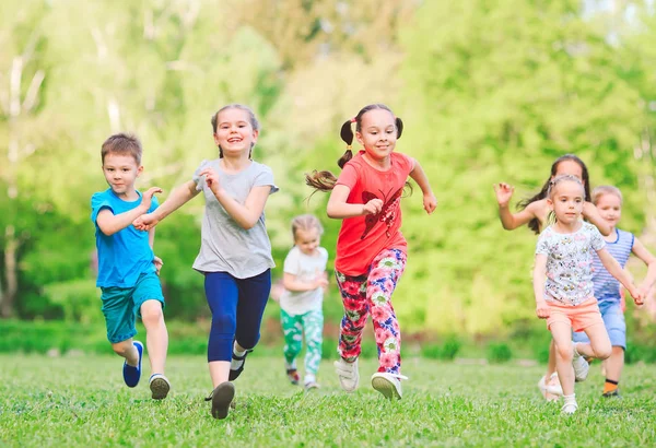 Viele verschiedene Kinder, Jungen und Mädchen, die an sonnigen Sommertagen in Freizeitkleidung durch den Park laufen. — Stockfoto