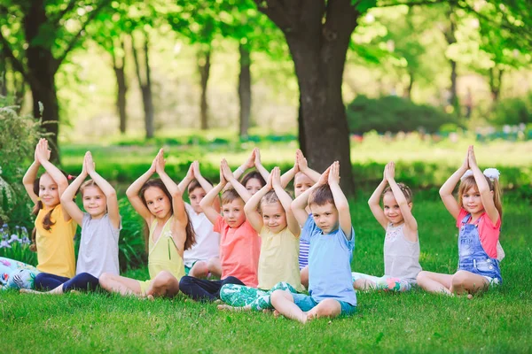 Eine große Gruppe von Kindern beim Yoga im Park auf dem Rasen sitzend — Stockfoto