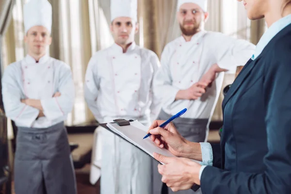 Restaurantleiter und seine Mitarbeiter in der Küche. Interaktion mit Küchenchef in der Großküche — Stockfoto